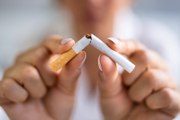 Zwei Hände zerknicken eine Zigarette.